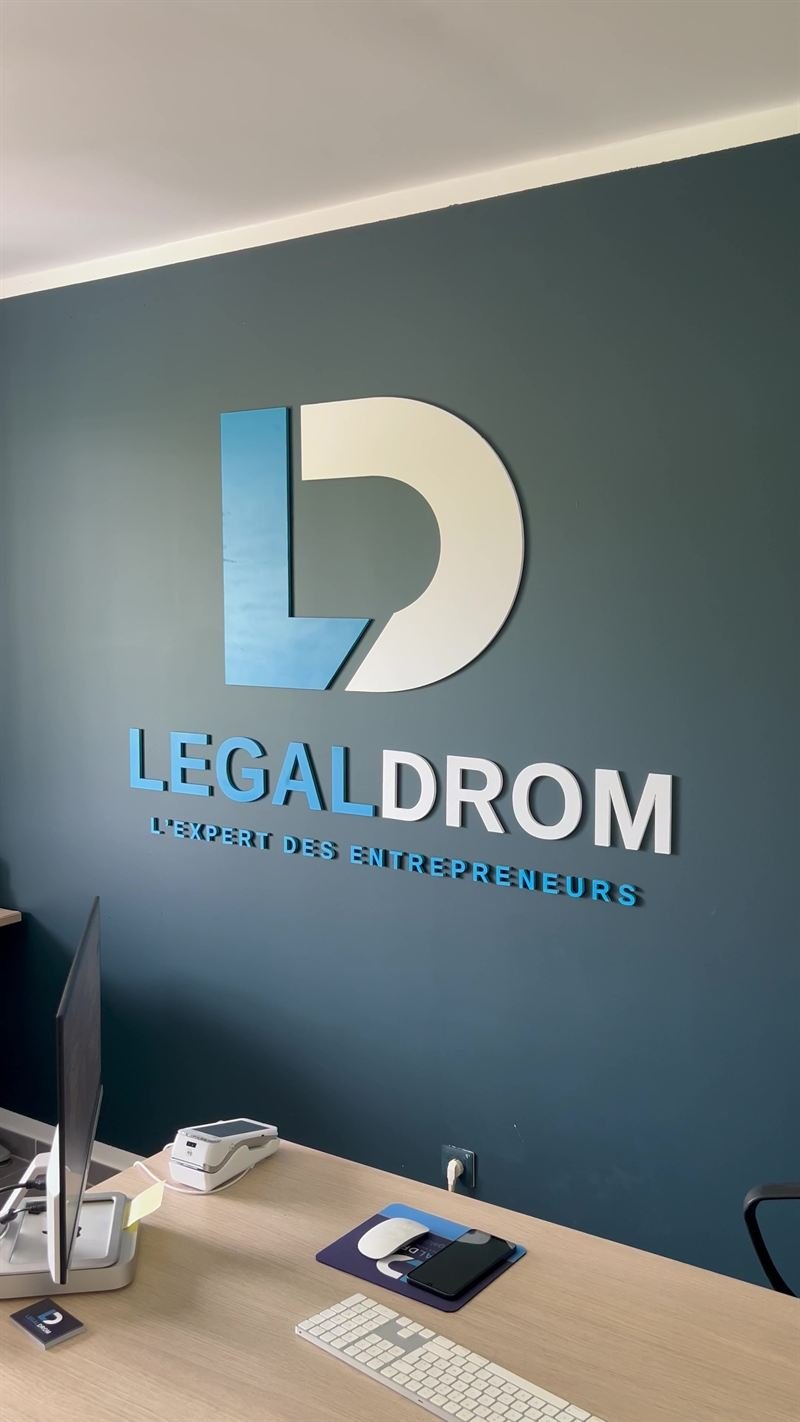 Legal Drom — Logo Legal Drom en relief sur un mur bleu