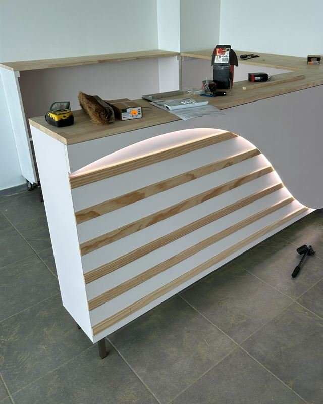 Comptoir d'accueil sur-mesure en lattes de bois avec éclairage LED, fabriqué par Madinéa