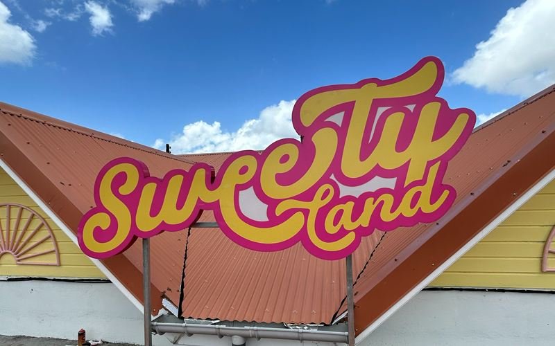 Enseigne Sweety Land en lettres en relief rose et jaune, installée sur une toiture en Martinique